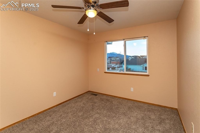 carpeted spare room with ceiling fan and a mountain view