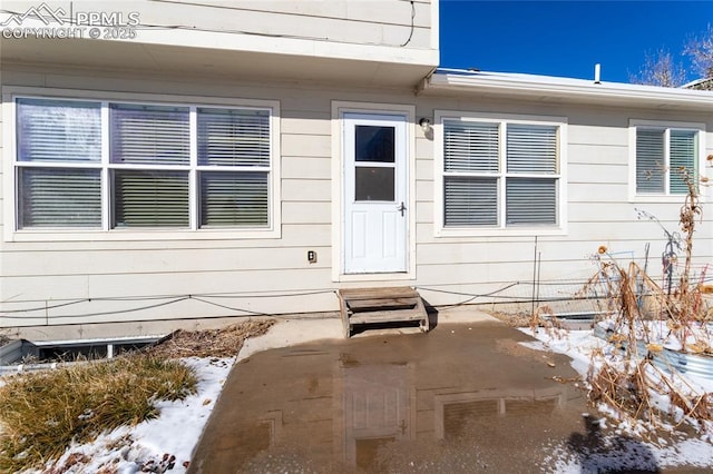 snow covered property entrance with a patio