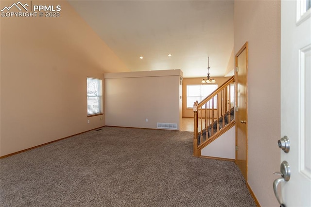 empty room with high vaulted ceiling, an inviting chandelier, and carpet floors