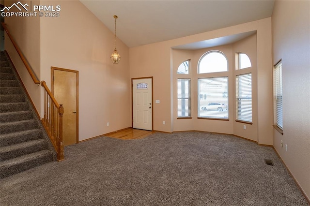 carpeted foyer entrance with high vaulted ceiling