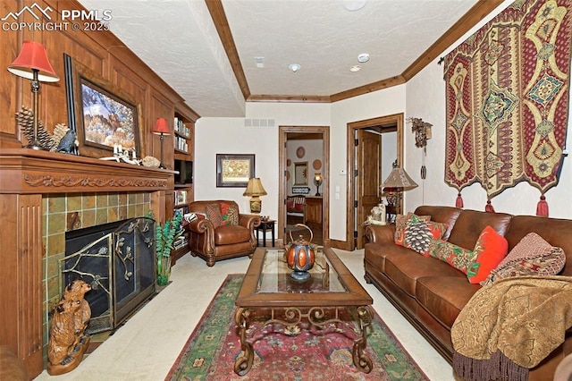 living room with crown molding, light colored carpet, a textured ceiling, and a tiled fireplace