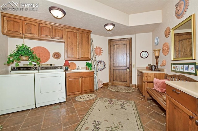 washroom with washer and clothes dryer, cabinets, sink, and a textured ceiling