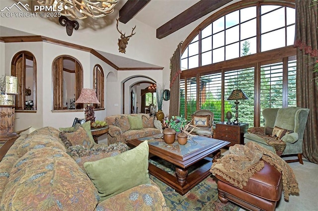 living room featuring carpet, a towering ceiling, beamed ceiling, and an inviting chandelier