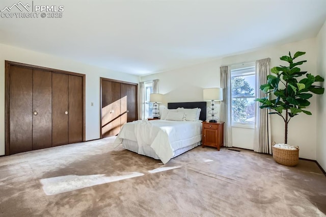 unfurnished bedroom featuring two closets and light colored carpet