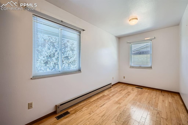 empty room featuring light wood-type flooring and baseboard heating