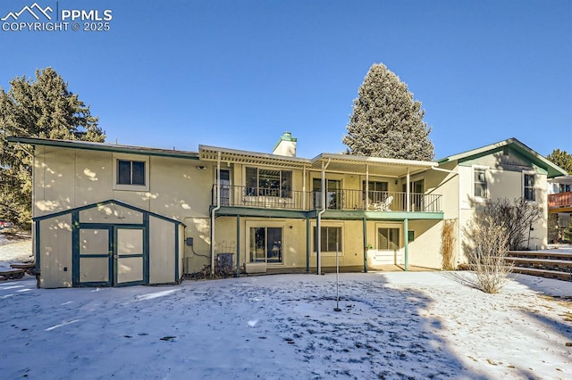 snow covered back of property featuring a balcony