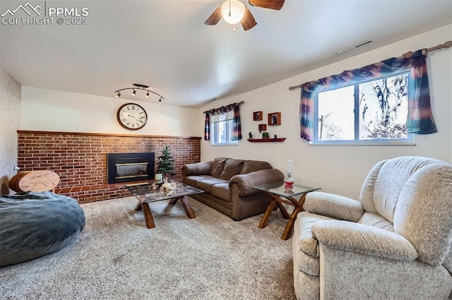 living room featuring ceiling fan, carpet, track lighting, and a fireplace