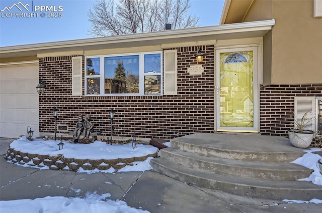 snow covered property entrance featuring a garage