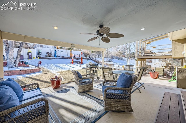 snow covered patio with an outdoor hangout area and ceiling fan