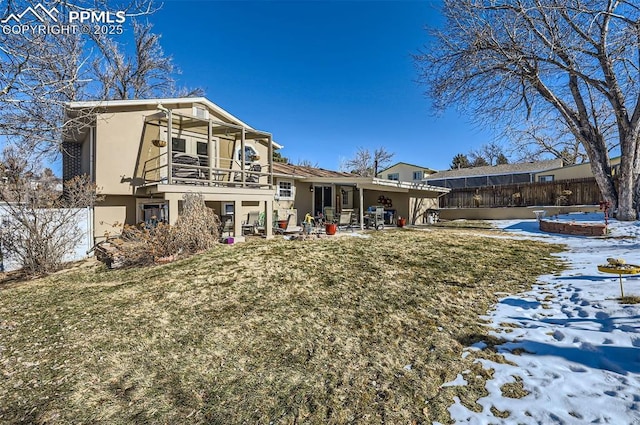 snow covered property featuring a balcony, a yard, and a patio area