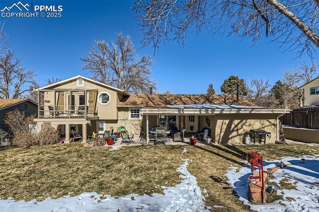 snow covered back of property featuring a lawn, a patio, and a balcony