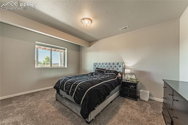 bedroom with a textured ceiling and dark colored carpet