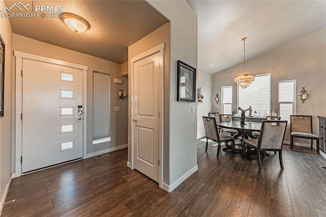 entrance foyer featuring a textured ceiling, dark hardwood / wood-style flooring, vaulted ceiling, and a notable chandelier