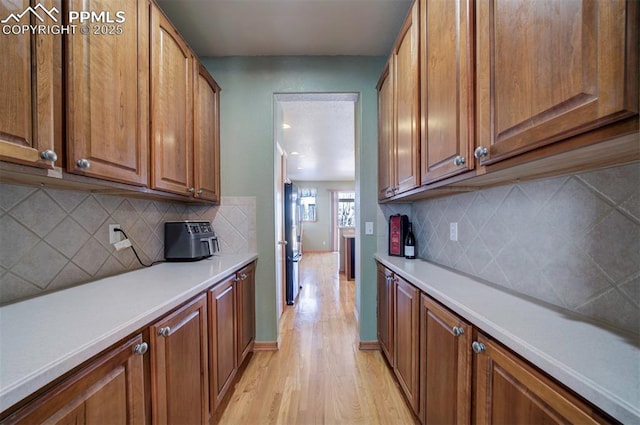 kitchen with light hardwood / wood-style floors, stainless steel refrigerator, and tasteful backsplash