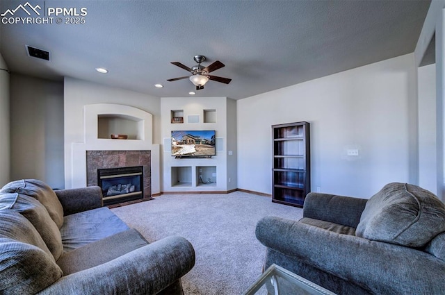 carpeted living room featuring a tile fireplace, ceiling fan, and a textured ceiling