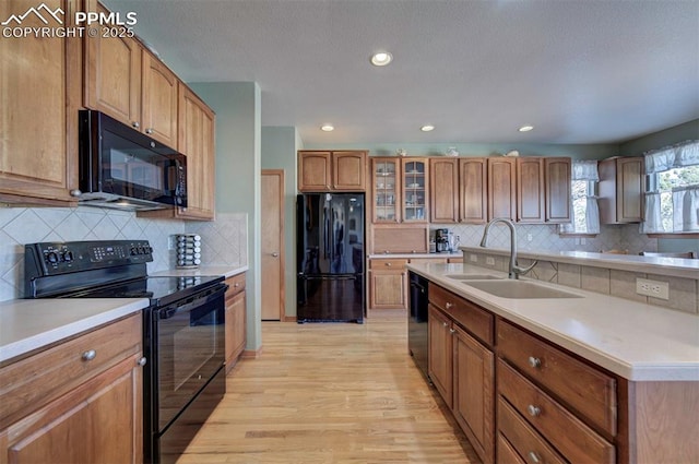 kitchen featuring black appliances, decorative backsplash, light hardwood / wood-style floors, and sink