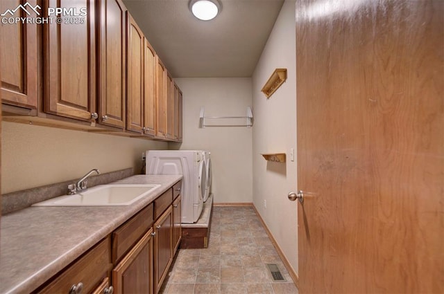 laundry area featuring washing machine and clothes dryer, sink, and cabinets