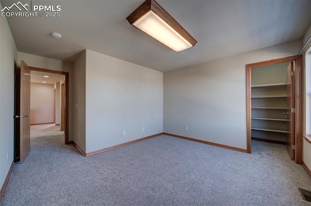 unfurnished bedroom featuring a walk in closet and light colored carpet