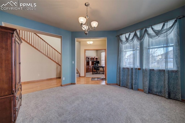 carpeted spare room with a chandelier