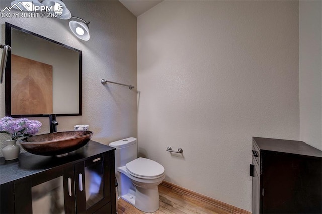 bathroom featuring wood-type flooring, vanity, and toilet