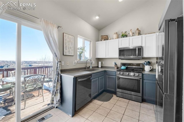 kitchen featuring white cabinetry, sink, vaulted ceiling, light tile patterned flooring, and appliances with stainless steel finishes