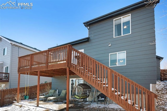 snow covered house with a patio area and a wooden deck