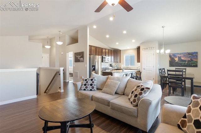 living room with ceiling fan with notable chandelier, dark hardwood / wood-style flooring, and high vaulted ceiling