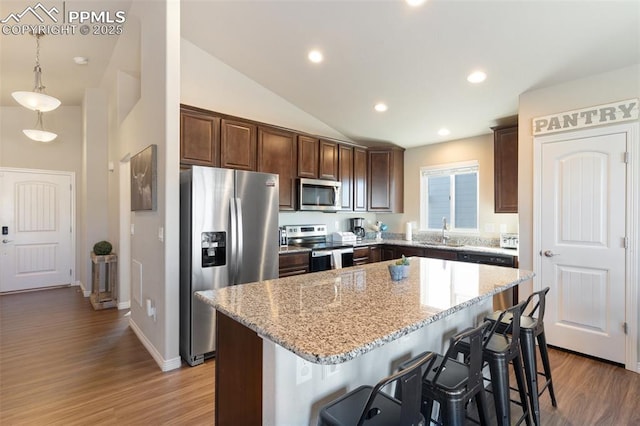 kitchen featuring a kitchen bar, appliances with stainless steel finishes, sink, a center island, and hanging light fixtures