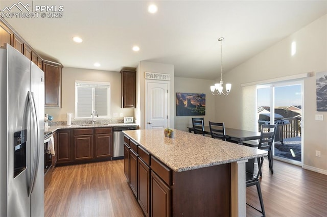 kitchen featuring an inviting chandelier, hanging light fixtures, light hardwood / wood-style floors, a kitchen island, and stainless steel appliances