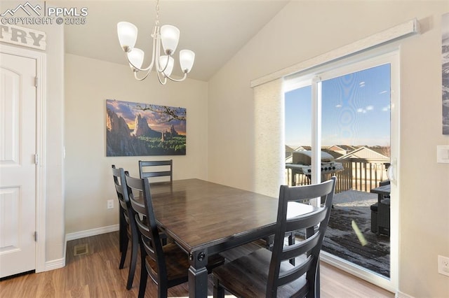 dining room featuring a chandelier, light hardwood / wood-style floors, and lofted ceiling