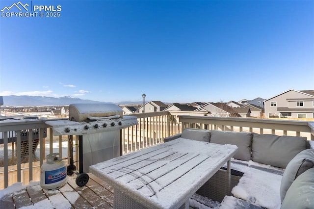 snow covered deck with a mountain view and grilling area