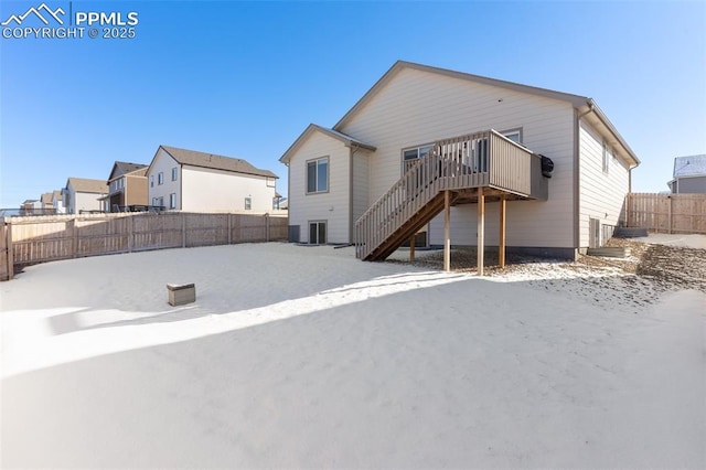 snow covered back of property with a wooden deck