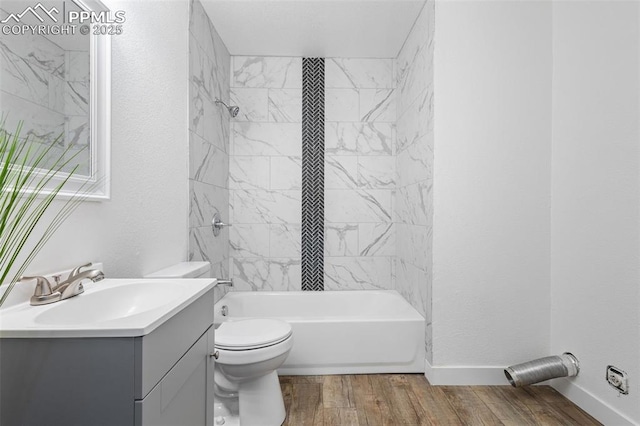 full bathroom featuring wood-type flooring, toilet, vanity, and tiled shower / bath