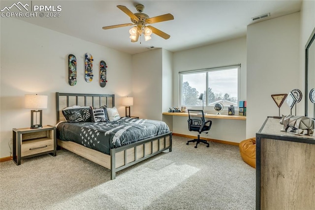 bedroom with ceiling fan, carpet, and built in desk