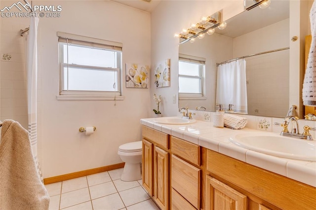 bathroom with a wealth of natural light, tile patterned floors, vanity, and toilet