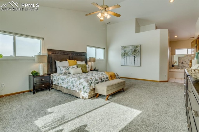 carpeted bedroom with ceiling fan, ensuite bathroom, and multiple windows