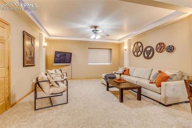 carpeted living room with ceiling fan and a tray ceiling