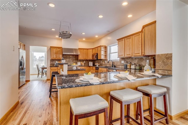 kitchen with a kitchen breakfast bar, appliances with stainless steel finishes, kitchen peninsula, and dark stone countertops