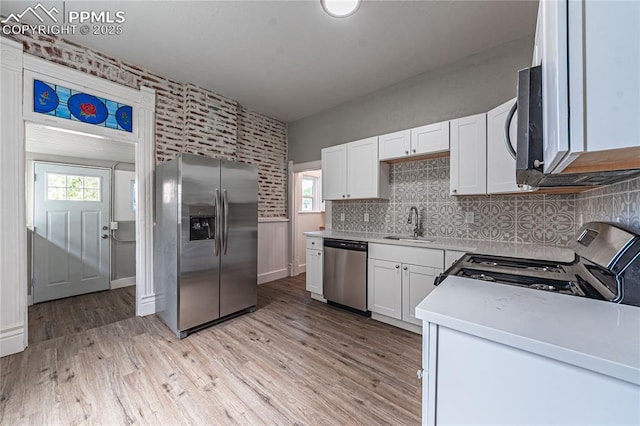 kitchen featuring white cabinets, appliances with stainless steel finishes, light wood-type flooring, and sink