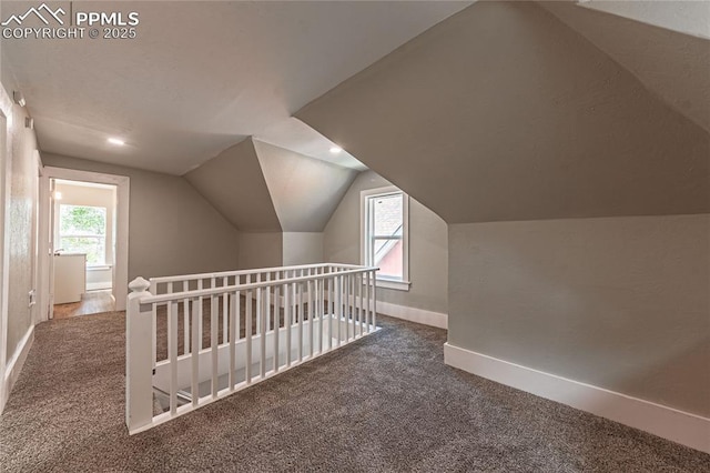 additional living space featuring dark carpet and lofted ceiling