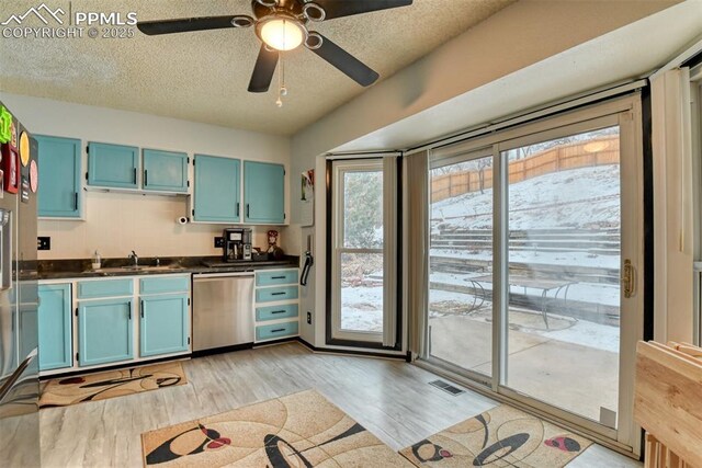 kitchen featuring sink, light wood-type flooring, stainless steel dishwasher, and a textured ceiling