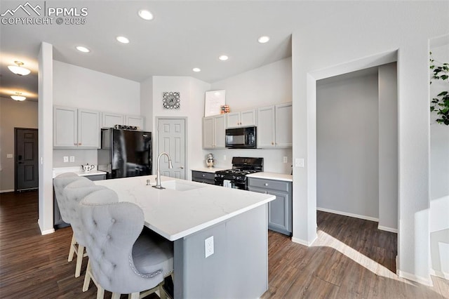 kitchen featuring sink, gray cabinetry, a kitchen bar, black appliances, and a center island with sink