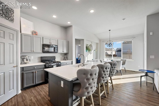 kitchen with gray cabinets, sink, hanging light fixtures, a kitchen island with sink, and black appliances