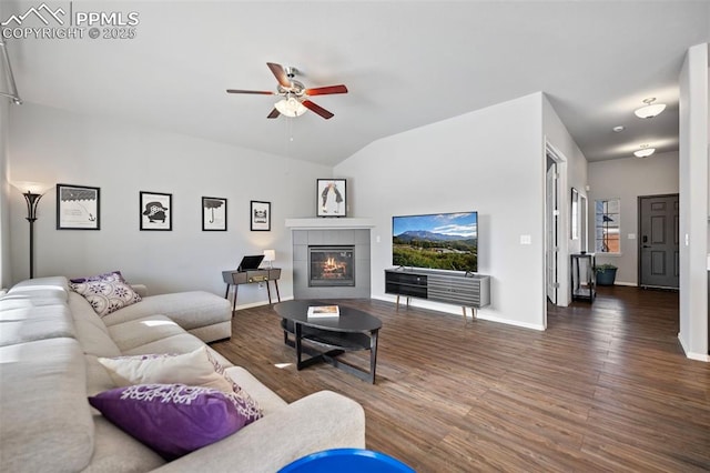 living room featuring dark wood-type flooring, ceiling fan, lofted ceiling, and a tile fireplace