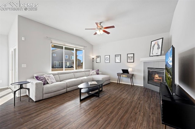 living room with a tile fireplace, vaulted ceiling, ceiling fan, and dark hardwood / wood-style flooring