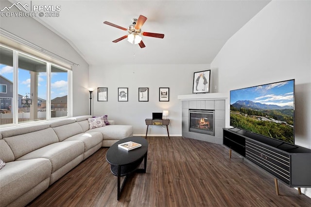 living room with a tiled fireplace, vaulted ceiling, ceiling fan, and dark hardwood / wood-style flooring