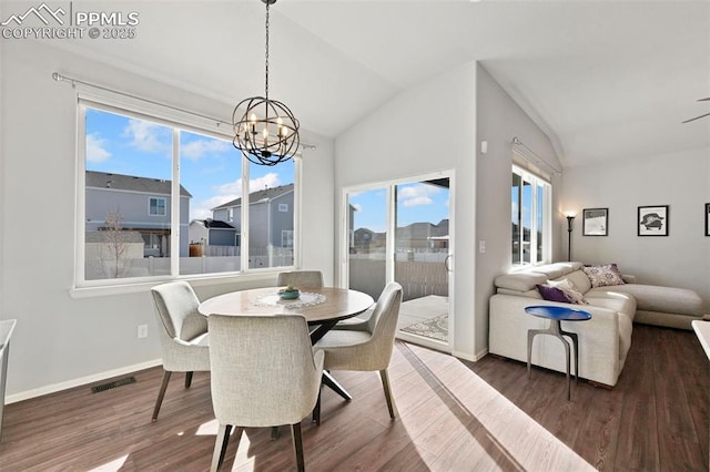 dining area with lofted ceiling, a healthy amount of sunlight, a chandelier, and dark hardwood / wood-style flooring