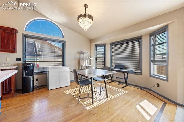 dining area featuring vaulted ceiling, light hardwood / wood-style flooring, and an inviting chandelier