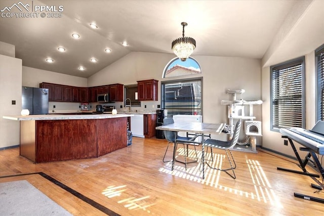 kitchen featuring a kitchen island, appliances with stainless steel finishes, decorative light fixtures, light hardwood / wood-style floors, and a chandelier