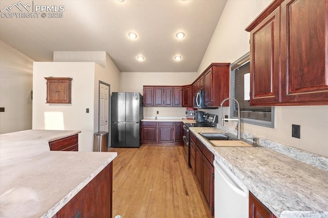 kitchen featuring appliances with stainless steel finishes, light hardwood / wood-style flooring, lofted ceiling, and sink